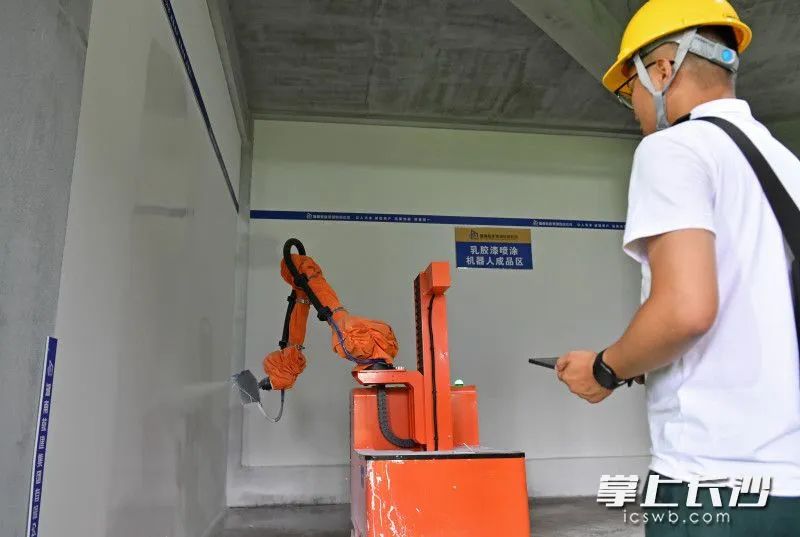 6月15日，望城區(qū)國欣·云境府項目工地上，工人操作室內(nèi)噴涂機器人在緊張忙碌。